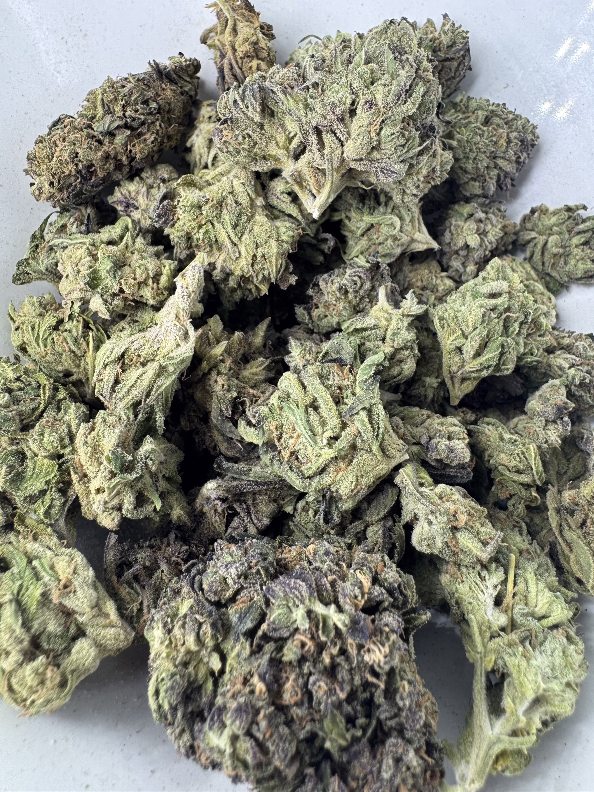 Bubba Kush 1 Close-up view of Bubba Kush cannabis buds showcasing their rich green and purple hues, highlighting the unique texture and quality.